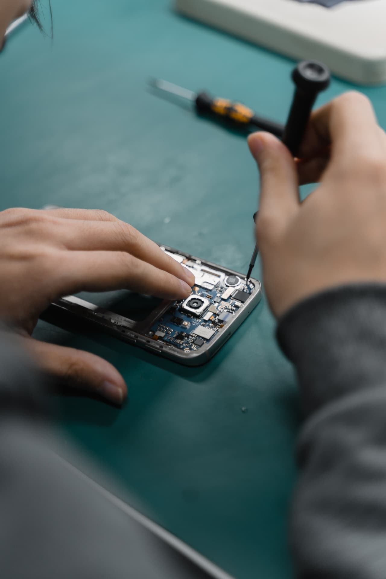 Praktikantas ir meistras prie darbo stalo EFIX elektronikos taisykloje Vilniuje